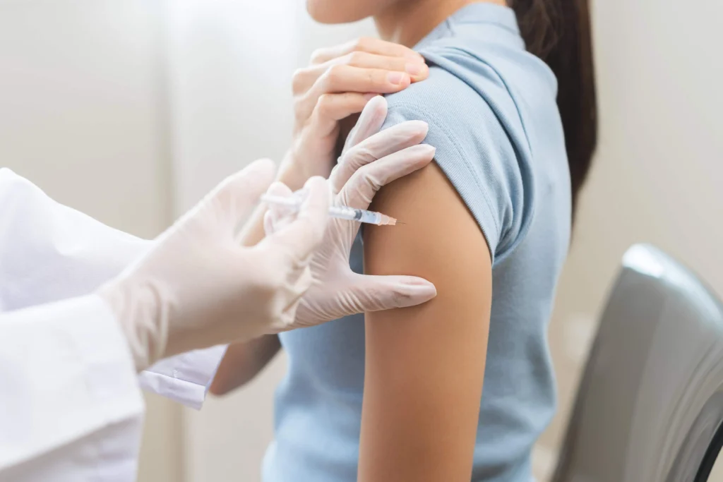 A Female receiving an injection on her shoulder while on Injection Therapy in Freeland, MI, at Evolution Aesthetics